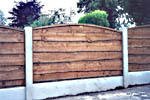 Garden fencing with concrete posts and arched top waney lap wooden fence panels.