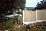 Building garden fence with concrete posts and plain gravel boards. Fencing panels are vertical close board.