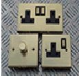 Single and double plug sockets in brass, and brass dimmer switch.