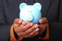 Man in suit with cupped hands at waist height holding a piggy bank. Represents a safe pair of hands for your savings.