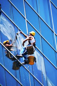 High Level window cleaner, suspended against the exterior of office building.