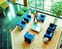 Looking down into reception area where cleaner is hoovering carpet between 6 chairs and table.