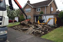 Image shows mini digger having dug up drive, and waggon with grab ready to load the debris.
