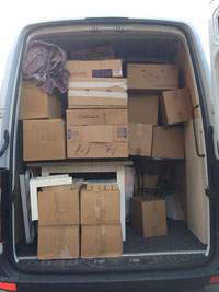 Picture of the rear of the van with back doors open, showing an almost full load, packed into cardboard boxes, ready to be taken to the new house.