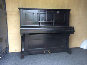 Black Piano inside removals van, ready to be secured and moved.