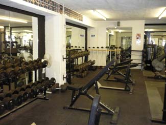 Rubber matted free weights area showing weight benches and dumb bells.