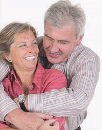 Image of older couple hugging, showing the ladies nice white teeth as she smiles at he partner.