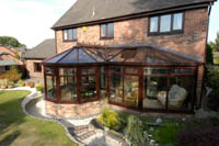 P-Shaped Conservatory at rear of house in dark wood grain effect.