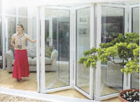 Image shows lady in red skirt opening folding white pvc-u patio doors.