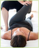 Lady in prone position having knee manipulation from her physiotherapist.
