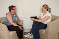 Physiotherapist Vickie cork conducting a free consultation with a lady, both seated. This involves gaining information to enable an holistic approach.