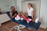 Male patient with Physiotherapist undergoing physiotherapy for sports injury to leg.