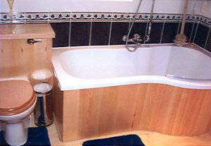 Bathroom with wooden bath panels, toilet seat and cistern in matching wood. Purpose built and made to measure by E. Beech Joinery Manufacturers covering Northwich in Cheshire.