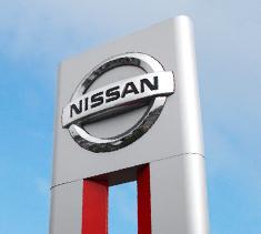 Nissan sign outside, taken from the groundlooking up at a brigt blue sky with thin cloud.