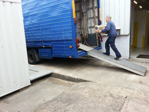 Man walking up ramp into rear of Grocotts Removals van carrying a package.