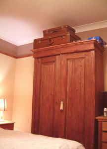 Wardrobe in bedroom with two cases on top.